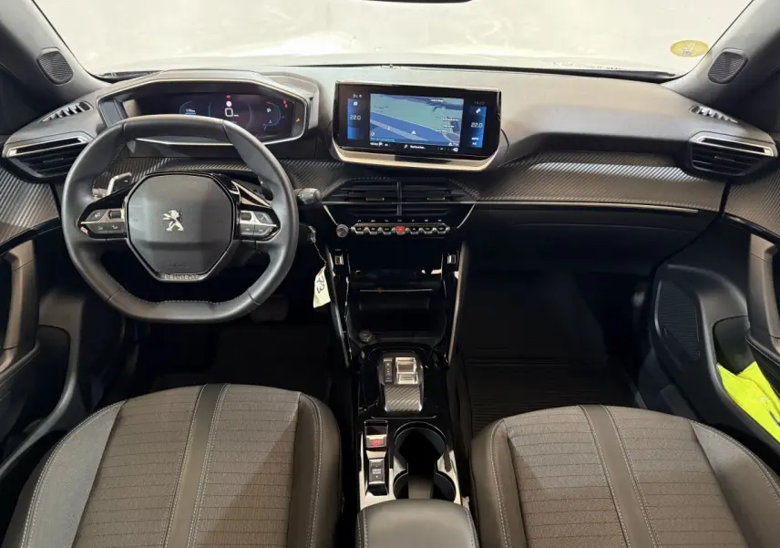 Vue intérieure avant du Peugeot 2008 gris clair 2023, tableau de bord moderne avec écran tactile central et volant compact.