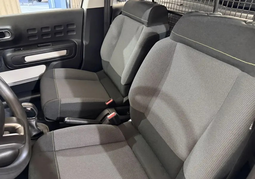 Vue intérieure côté conducteur de la Citroën C3 2021, sièges tissu gris avec surpiqûres jaunes et séparation grillagée.