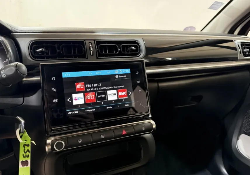 Vue intérieure du tableau de bord de la Citroën C3 blanche, avec écran tactile central affichant des stations radio.