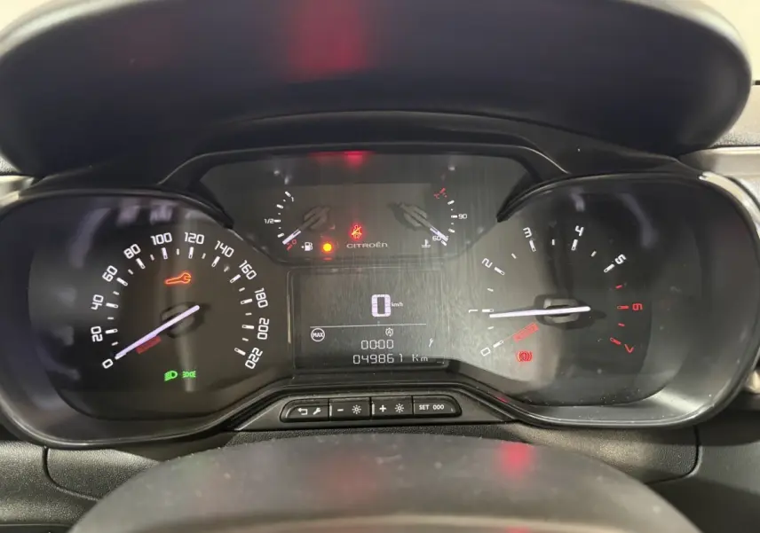 Tableau de bord de Citroën C3 blanc, affichage numérique central et compteurs analogiques en vue frontale rapprochée.