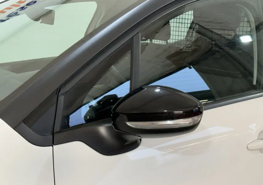 Gros plan sur le rétroviseur noir côté conducteur d'une Citroën C3 blanche, avec fenêtre et partie de la portière visibles.