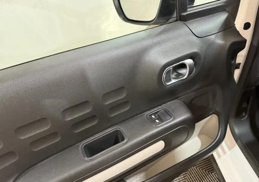 Vue rapprochée de la porte avant gauche noire et beige de la Citroën C3 blanche, avec commandes de vitres et poignée intégrée.