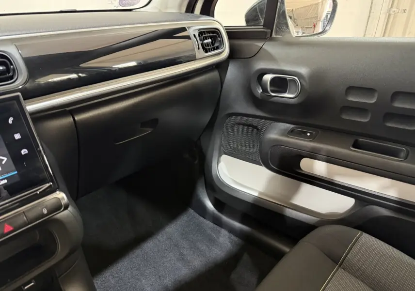 Intérieur côté passager de la Citroën C3 blanc, tableau de bord noir brillant et garniture de porte bicolore.