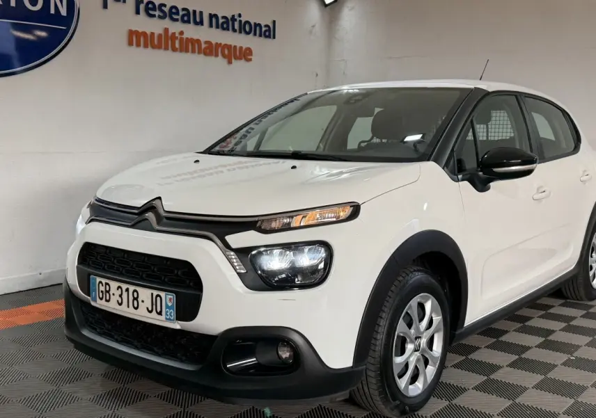 Vue 3/4 avant droite d'une Citroën C3 blanche 2021 avec phares allumés et détails noirs contrastants.