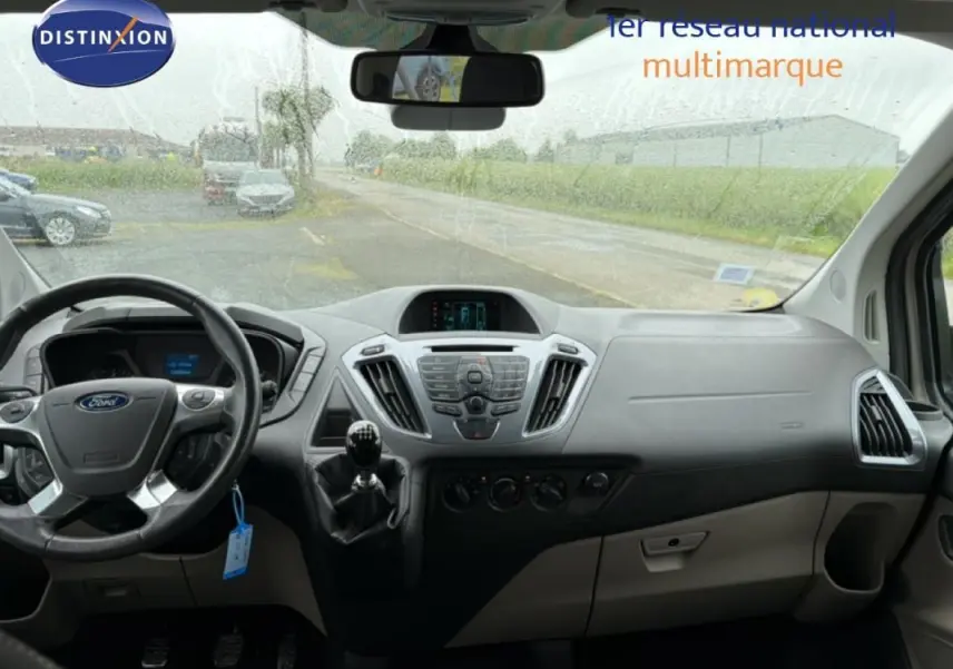 Vue intérieure du tableau de bord gris du Ford Tourneo Custom 2015 avec volant, levier de vitesse manuel et écran central.