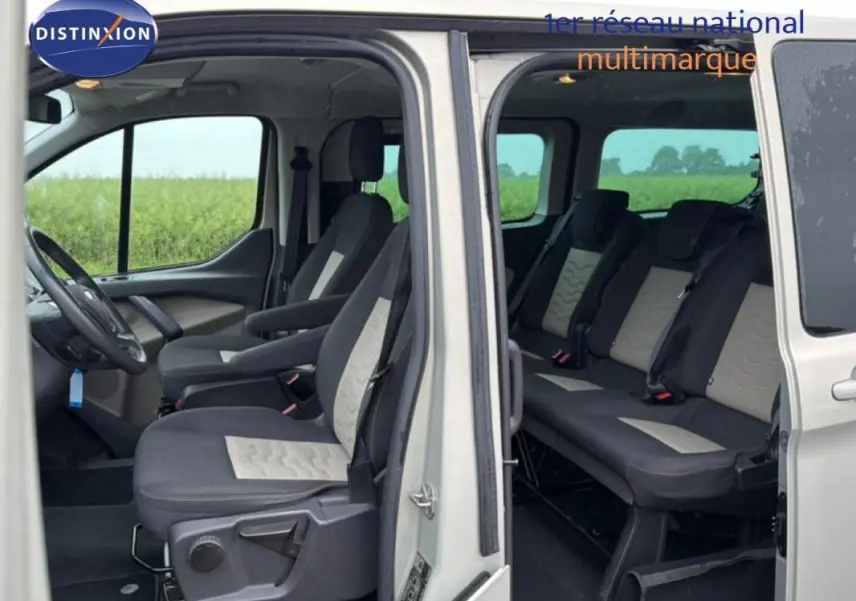 Vue intérieure côté gauche du Ford Tourneo Custom gris foncé, montrant les sièges avant et arrière avec portes ouvertes.