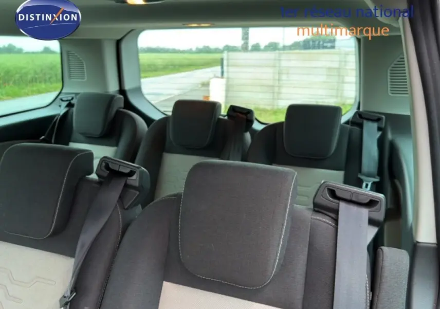 Vue intérieure arrière du Ford Tourneo Custom gris foncé, montrant les sièges passagers en tissu avec ceintures de sécurité.