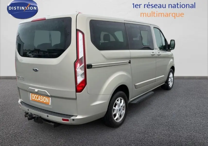 Vue 3/4 arrière droite du Ford Tourneo Custom gris foncé avec marchepieds et attelage visible.