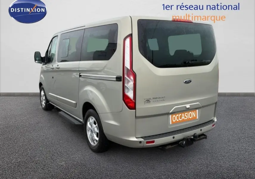 Vue 3/4 arrière droite d’un Ford Tourneo Custom gris clair avec attelage et vitres surteintées.