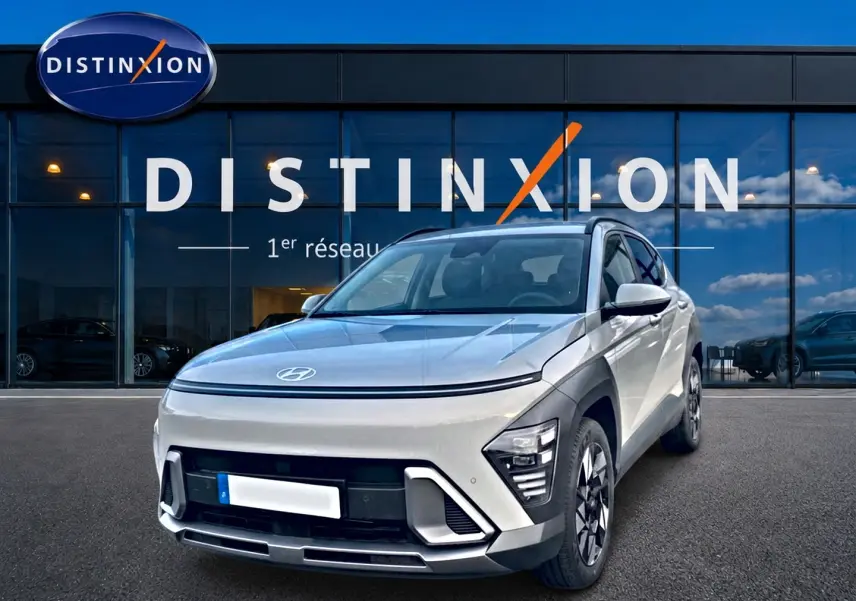Hyundai Kona gris 2025 en 3/4 avant droit, avec feux LED et jantes alliage devant showroom Distinxion.