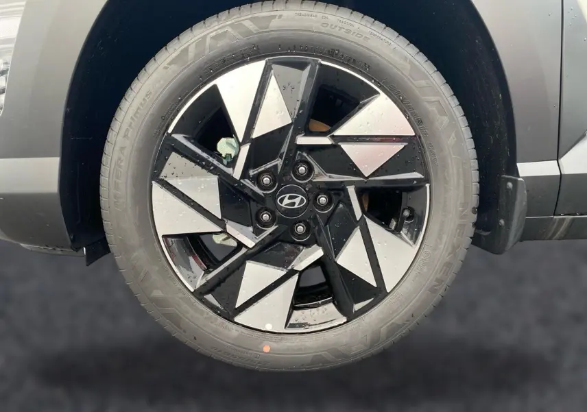 Gros plan sur la roue avant droite du Hyundai Kona gris 2025, jante alliage noire et argentée au design géométrique.