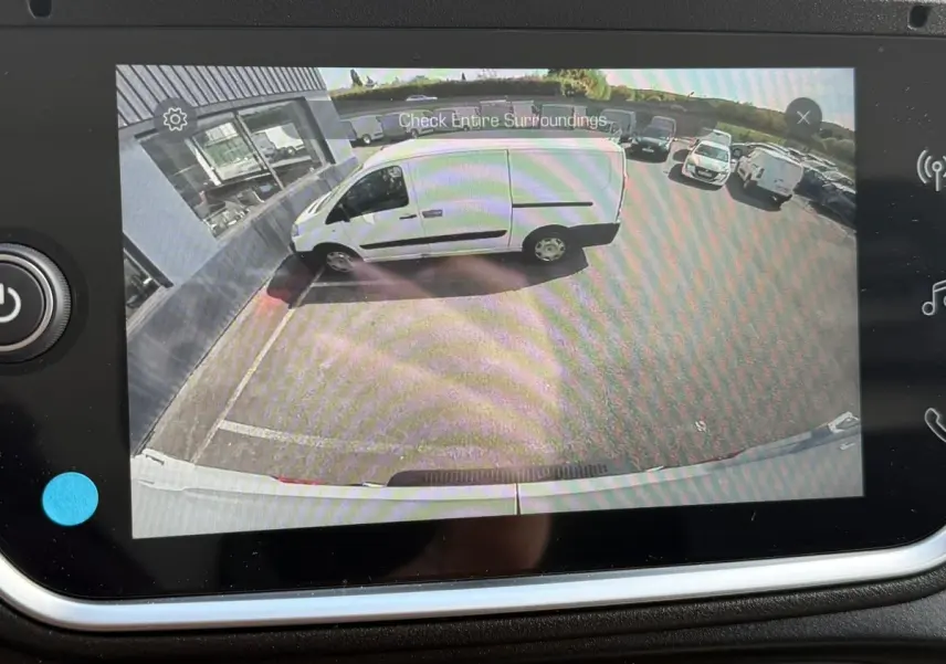 Vue caméra arrière montrant un utilitaire blanc Iveco Daily 35S18 garé côté gauche près d’un bâtiment.