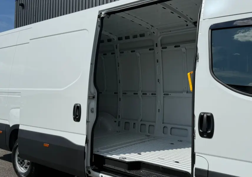 Vue latérale gauche d’un Iveco Daily blanc 2026 avec porte coulissante ouverte montrant l’intérieur vide du fourgon.