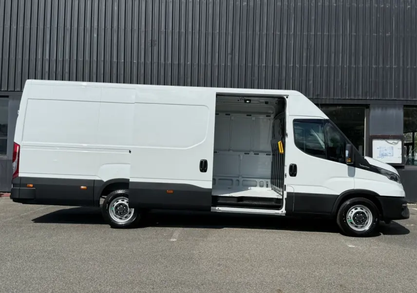 Fourgon Iveco Daily blanc vu de profil droit avec porte latérale coulissante ouverte montrant l’espace de chargement vide.