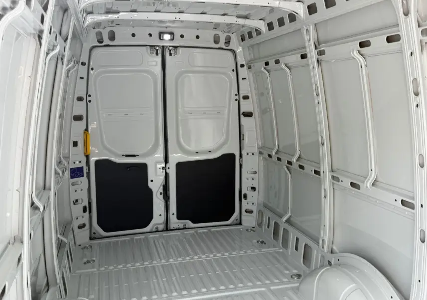 Vue intérieure arrière du fourgon Iveco Daily blanc 2026, montrant l’espace de chargement vide et les portes battantes.