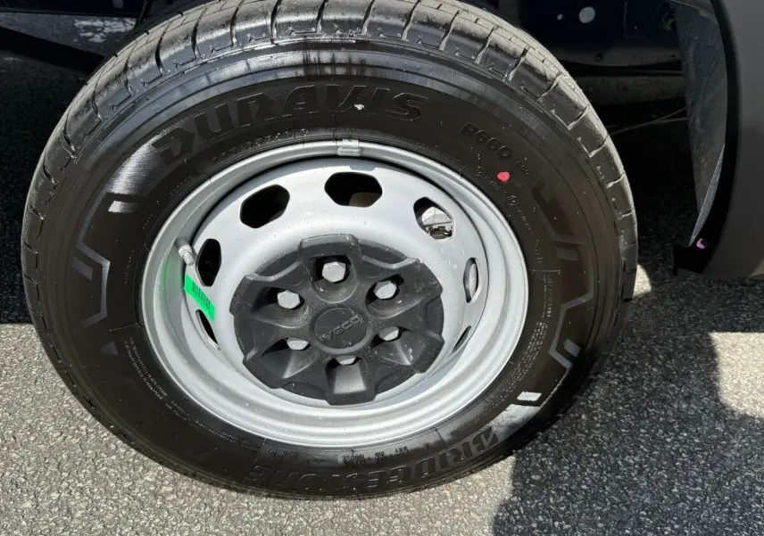 Gros plan sur la roue avant droite d’un Iveco Daily blanc, mettant en valeur la jante acier et le pneu Bridgestone Duravis.