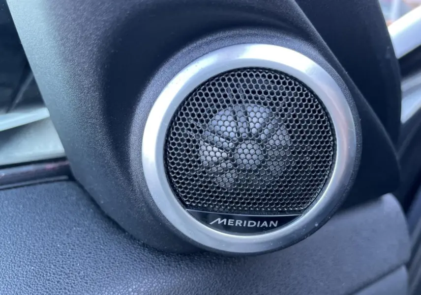 Gros plan sur le haut-parleur Meridian noir et argenté côté gauche dans l'habitacle du Range Rover Evoque gris 2019.