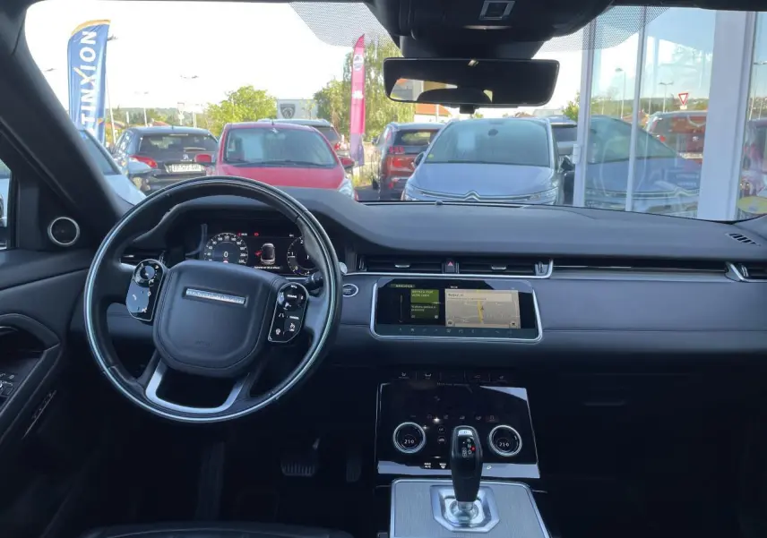 Tableau de bord et volant noir du Range Rover Evoque 2019 vus de face avec écran tactile central allumé.