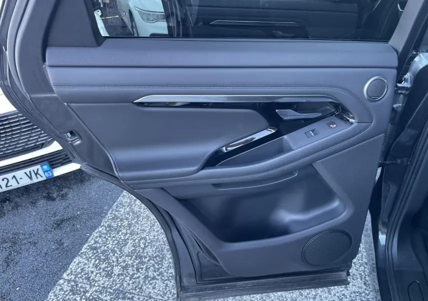 Porte arrière gauche ouverte du Range Rover Evoque gris, avec garniture intérieure en cuir et commandes de fenêtre.