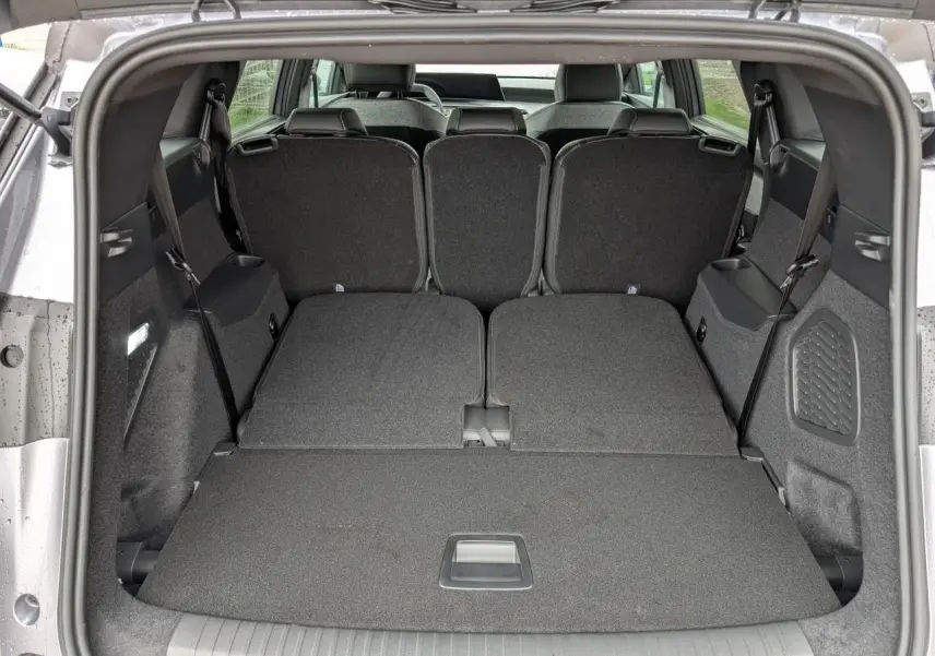 Coffre ouvert du Peugeot 5008 gris Artense avec banquette arrière rabattue, offrant un espace de chargement plat.