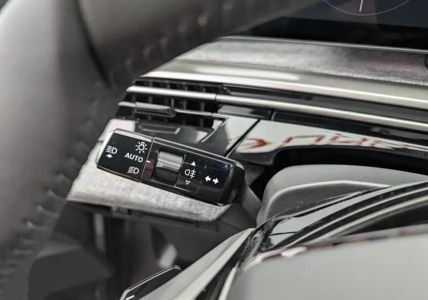 Gros plan sur la commande des feux et clignotants à gauche du volant du Peugeot 5008 gris Artense 2025.