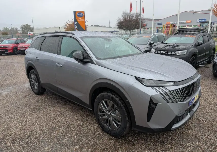Peugeot 5008 gris Artense vue 3/4 avant droit sous la pluie avec calandre noire et jantes alliage 18 pouces.