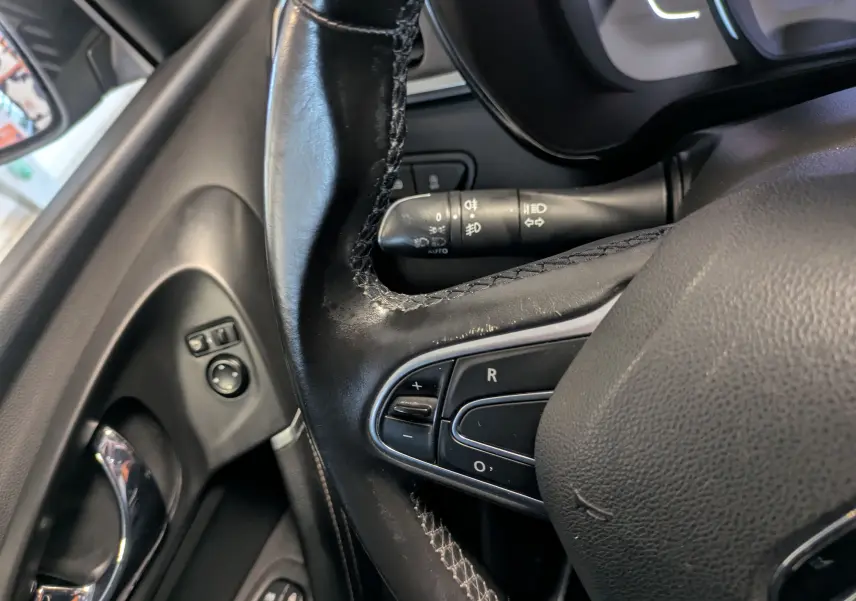 Gros plan sur le volant en cuir noir et les commandes de régulateur de vitesse du Renault Kadjar gris, côté conducteur.