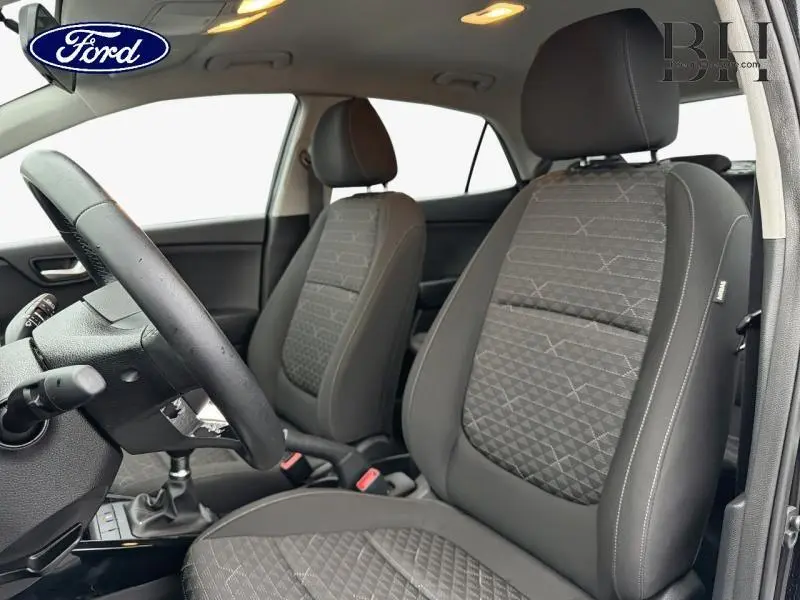 Vue intérieure côté conducteur montrant les sièges tissu Atlanta gris et volant cuir d'une KIA RIO noir ébène 2018.