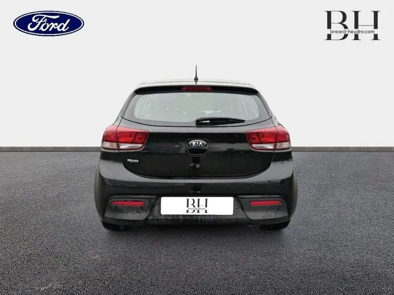 Vue arrière d'une KIA Rio noire Ébène de 2018, avec feux rouges et logo central bien visibles.