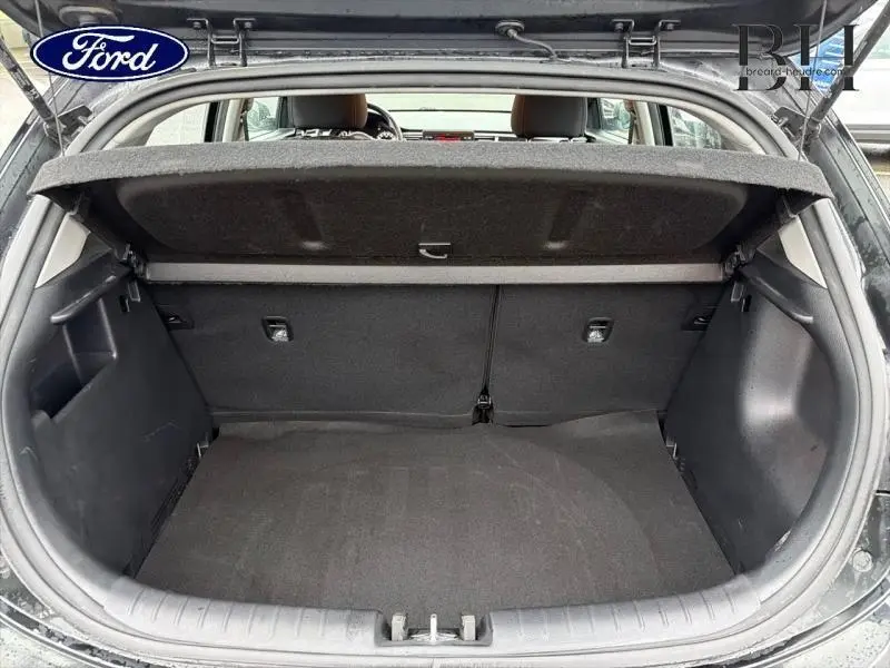 Coffre ouvert vu de l'arrière d'une KIA Rio noir Ébène, montrant l'espace de chargement et la tablette cache-bagages.