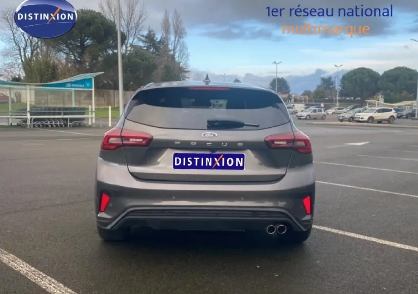 Vue arrière d'une Ford Focus gris foncé 2024 avec feux LED, double sortie d'échappement et vitres surteintées.