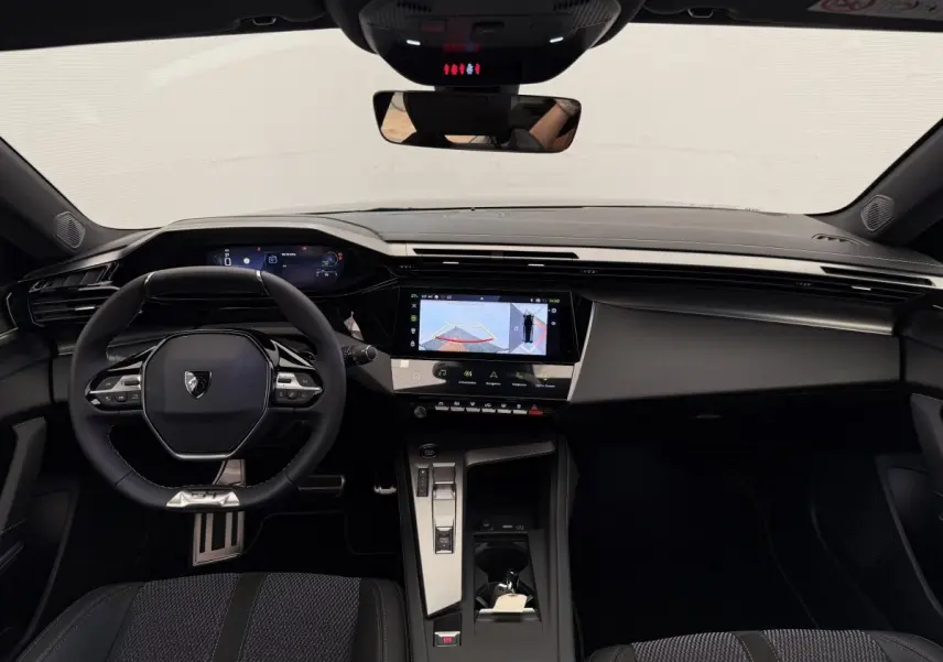 Vue intérieure frontale du tableau de bord noir du Peugeot 308 Hybrid 136 e-DCS6 GT avec écran tactile central et volant multifonctions.