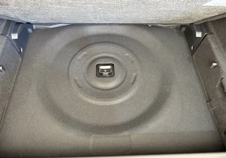 Vue rapprochée du coffre de la Peugeot 308 Hybrid 136 e-DCS6 GT 2024, montrant le compartiment gris foncé pour roue de secours.