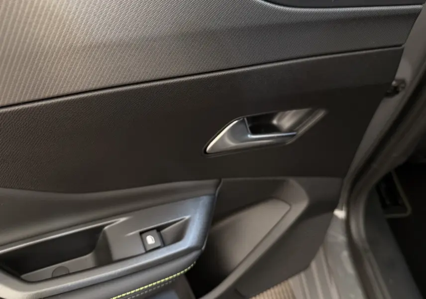 Détail de la porte intérieure côté conducteur de la Peugeot 308 Hybrid 136 e-DCS6 GT 2024 en gris foncé, avec poignée et bouton de verrouillage.