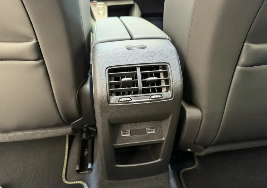Vue rapprochée de la console centrale arrière avec aérateurs et ports USB dans l’habitacle gris foncé d’une Peugeot 308 Hybrid 2024.