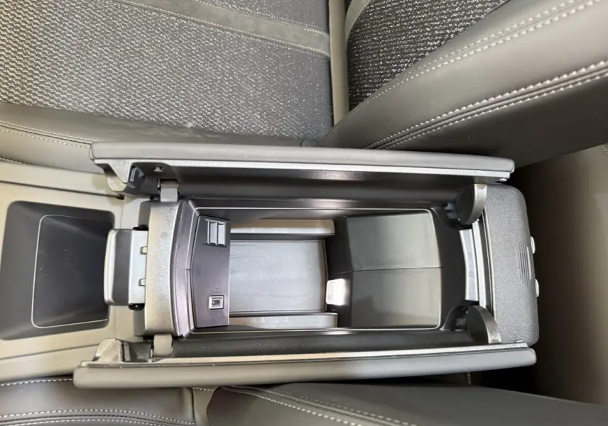 Vue plongeante sur l'accoudoir central ouvert en cuir gris foncé de la Peugeot 308 Hybrid 136 e-DCS6 GT 2024.