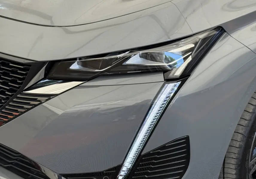 Gros plan sur le phare avant droit gris foncé du Peugeot 308 Hybrid 136 e-DCS6 GT 2024 avec éclairage LED distinctif.