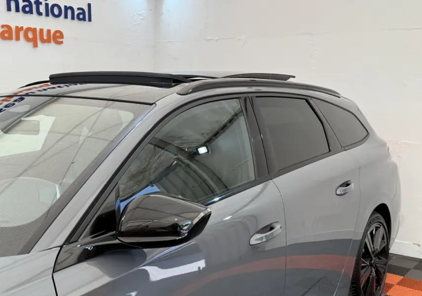 Vue latérale droite d’un Peugeot 308 Hybrid 136 e-DCS6 GT gris foncé avec rétroviseur noir brillant et toit ouvrant.