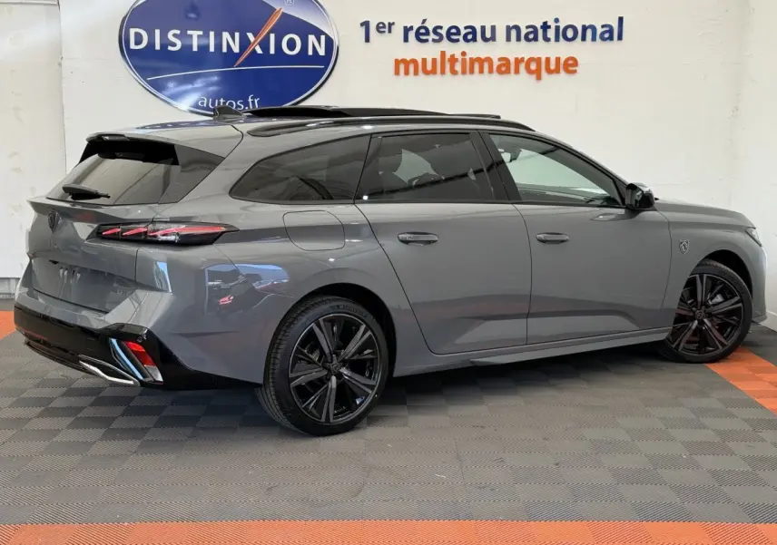 Peugeot 308 Hybrid 136 e-DCS6 GT gris foncé vue 3/4 arrière droit, jantes noires et toit ouvrant panoramique.