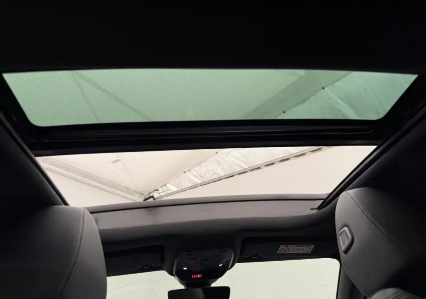 Vue intérieure du toit ouvrant panoramique et des appuie-têtes en cuir gris foncé d'une Peugeot 308 Hybrid 2024.