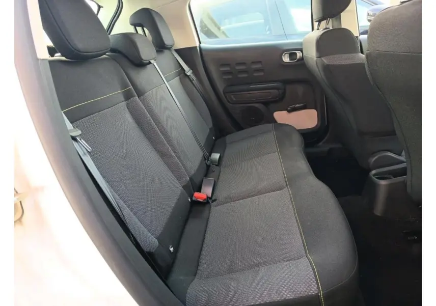 Vue intérieure côté gauche des sièges arrière noirs avec surpiqûres jaunes dans une Citroën C3 blanche de 2021.