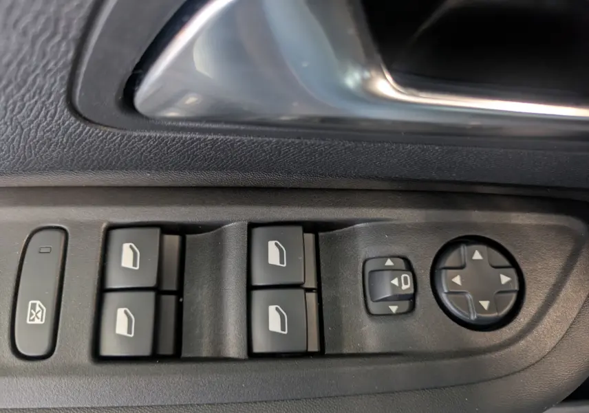 Détail des commandes des vitres et rétroviseurs côté conducteur sur porte intérieure noire d'une Citroën C4 Bleu Eclipse.