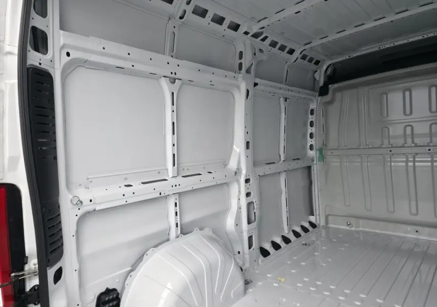 Intérieur du fourgon Peugeot Boxer blanc vu de l'arrière, montrant la structure tôlée et l'espace de chargement vide.