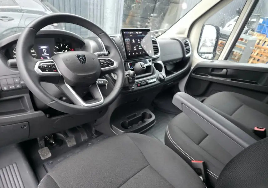 Vue intérieure côté conducteur du Peugeot Boxer Fourgon 2025, montrant le volant cuir et l’écran tactile central.