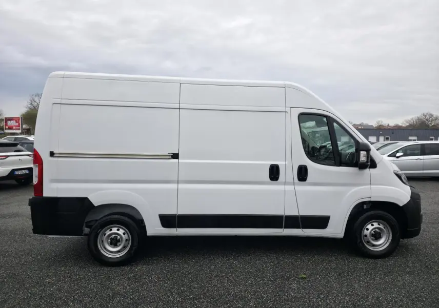 Vue latérale droite d’un Peugeot Boxer Fourgon blanc avec porte coulissante et roues acier 15 pouces.