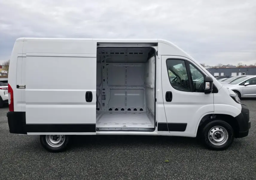 Vue latérale droite d'un Peugeot Boxer Fourgon blanc avec porte coulissante ouverte montrant l'espace de chargement vide.