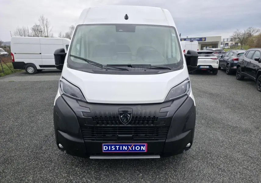 Vue avant d'un Peugeot Boxer Fourgon blanc avec calandre noire et logo lion distinctif, sur parking extérieur.