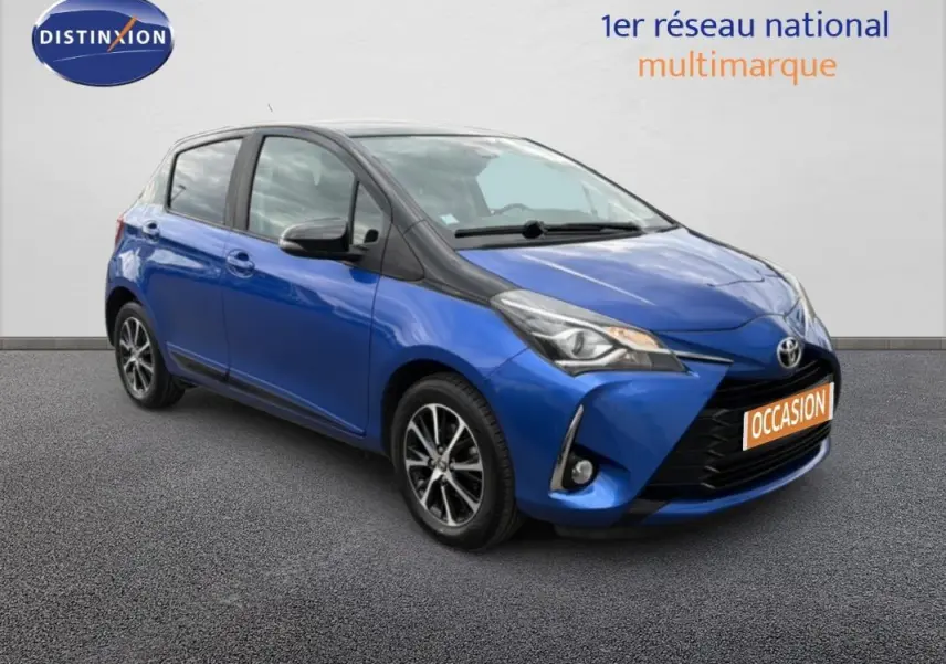 Toyota Yaris bleu foncé en 3/4 avant droit, avec jantes alliage et phares antibrouillard visibles.