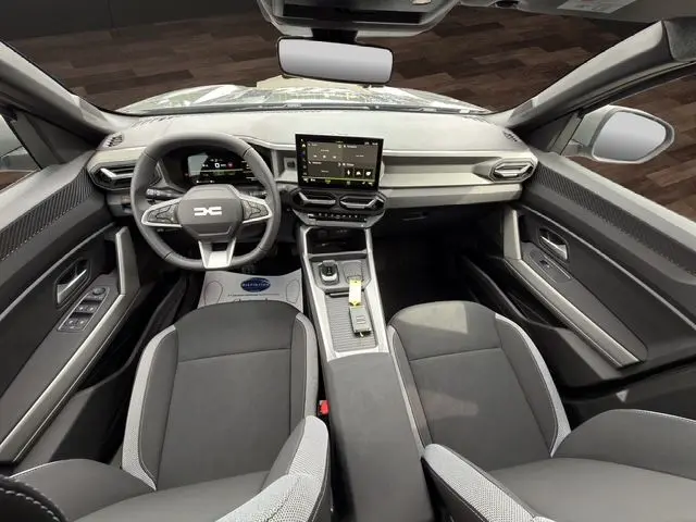 Vue intérieure avant du Dacia Bigster gris foncé 2026, avec tableau de bord moderne et écran tactile central.