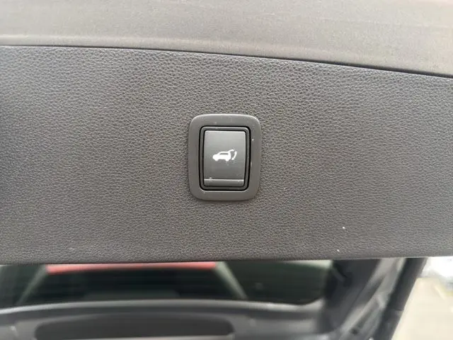 Bouton d'ouverture électrique du coffre sur la partie intérieure du hayon d'un Dacia Bigster gris foncé.